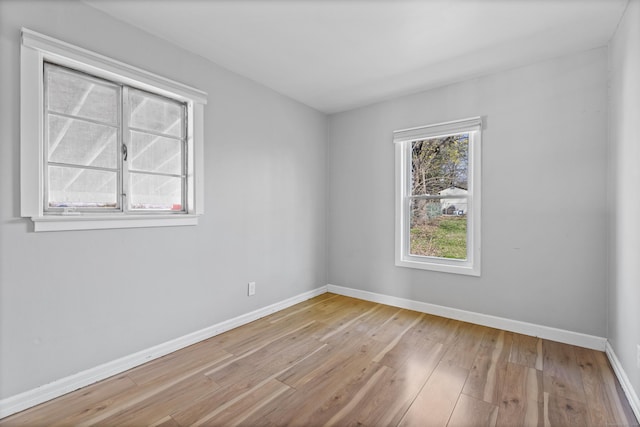 spare room with baseboards and hardwood / wood-style flooring