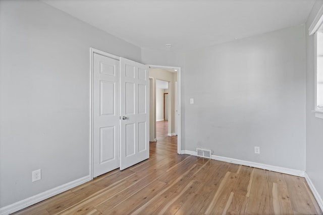 unfurnished bedroom featuring light wood-type flooring, baseboards, and visible vents