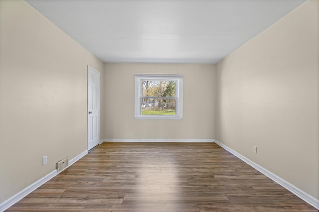 empty room featuring dark wood finished floors, baseboards, and visible vents
