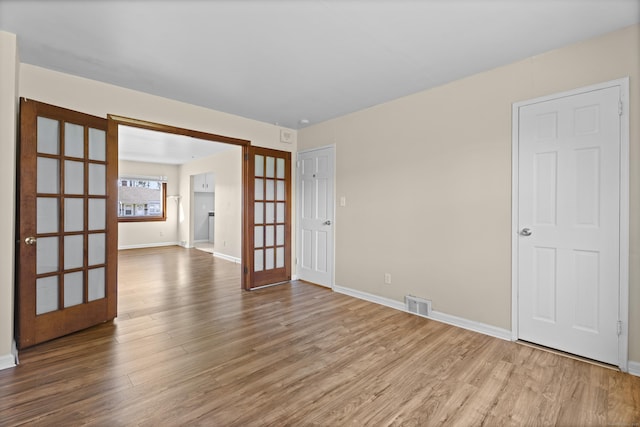 spare room with baseboards, french doors, wood finished floors, and visible vents