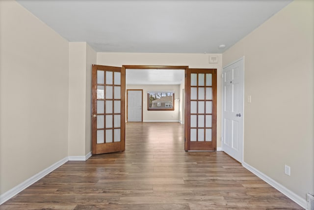 unfurnished room featuring baseboards, french doors, and wood finished floors