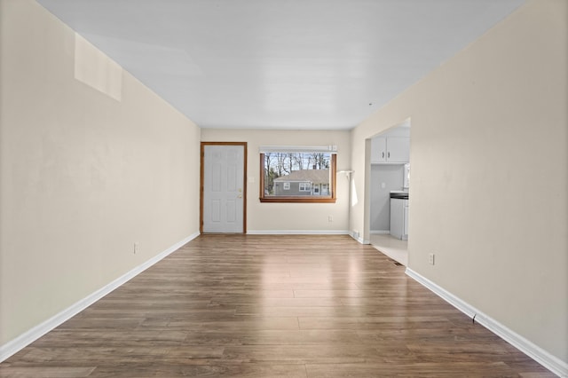 unfurnished living room featuring baseboards and dark wood-style floors