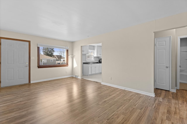 unfurnished living room featuring baseboards, visible vents, and light wood finished floors