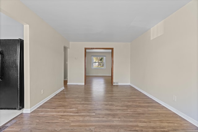 empty room with visible vents, baseboards, and wood finished floors