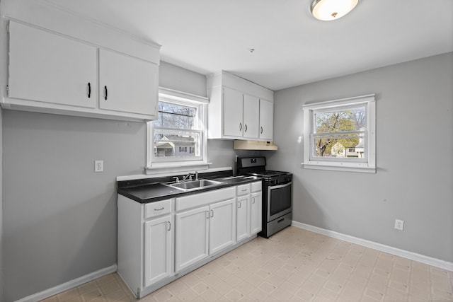 kitchen with plenty of natural light, under cabinet range hood, a sink, gas stove, and baseboards