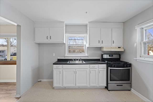 kitchen with under cabinet range hood, gas stove, white cabinetry, and a sink