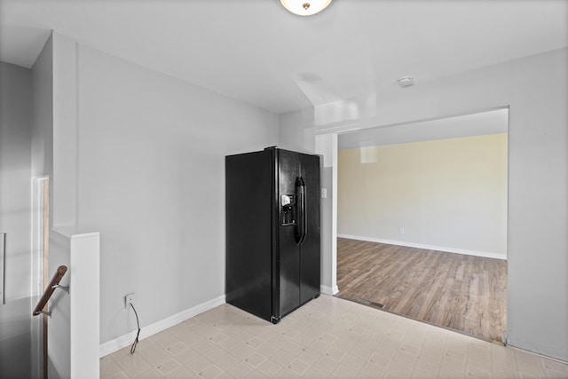 interior space with black refrigerator with ice dispenser, baseboards, and light wood-style flooring