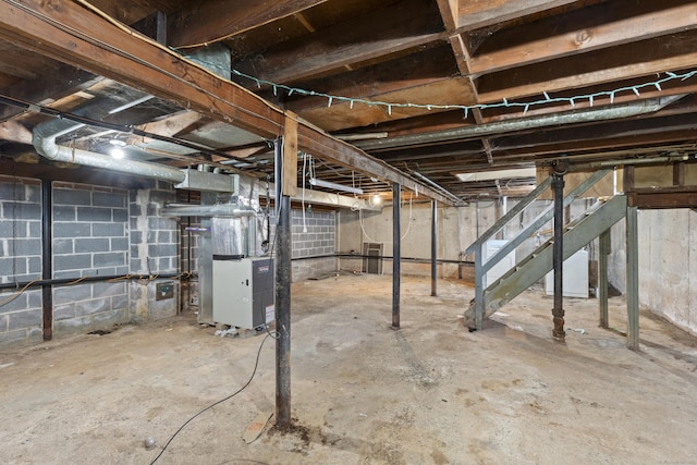 unfinished basement featuring heating unit and stairs