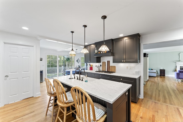11 Knollwood Dr, Newtown, CT 06470 - kitchen featuring decorative backsplash, a kitchen breakfast bar, a center island with sink, stainless steel gas stovetop, and light wood-style flooring