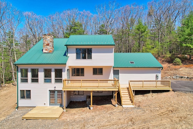back of property featuring metal roof, a deck, french doors, and a chimney