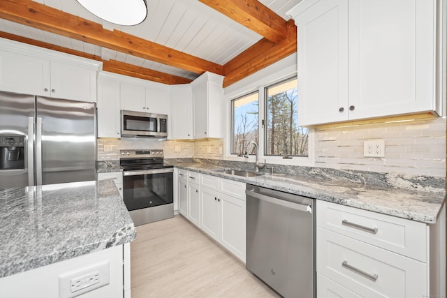 kitchen with tasteful backsplash, light stone countertops, stainless steel appliances, a sink, and beam ceiling