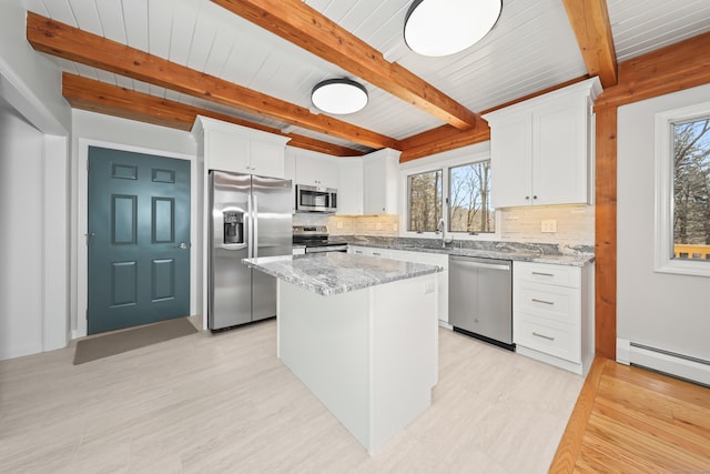kitchen featuring beamed ceiling, a wealth of natural light, appliances with stainless steel finishes, and decorative backsplash