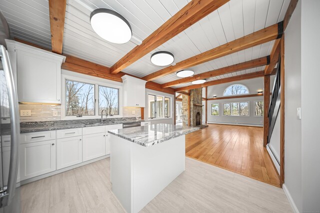 kitchen featuring light stone countertops, stainless steel appliances, backsplash, a center island, and open floor plan
