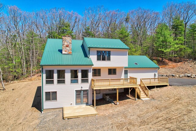 back of house featuring a deck, french doors, a chimney, and metal roof
