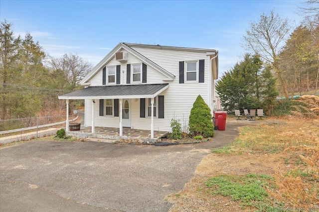 view of front of house with fence, a porch, and metal roof