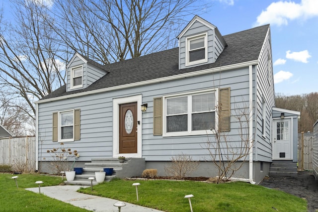 new england style home with fence, a shingled roof, entry steps, and a front yard