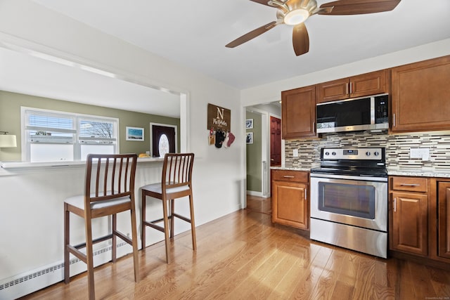 kitchen featuring backsplash, light wood-style flooring, a breakfast bar area, and stainless steel appliances