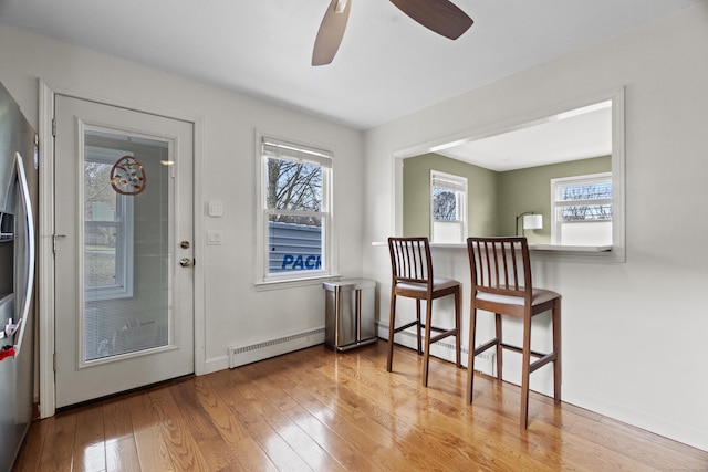 interior space with baseboards, wood finished floors, a ceiling fan, and baseboard heating