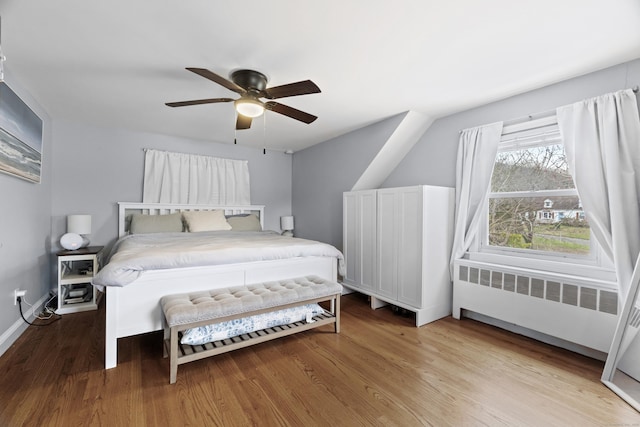 bedroom with radiator, wood finished floors, baseboards, and ceiling fan