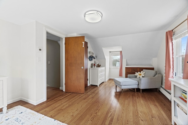 bedroom with baseboards, light wood finished floors, and baseboard heating