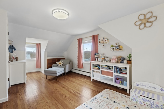 additional living space featuring a baseboard radiator, vaulted ceiling, wood finished floors, and baseboards