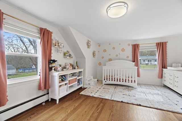 bedroom featuring baseboards, baseboard heating, wood finished floors, and vaulted ceiling