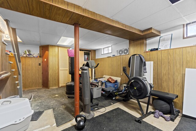 workout area with wooden walls, a paneled ceiling, and plenty of natural light