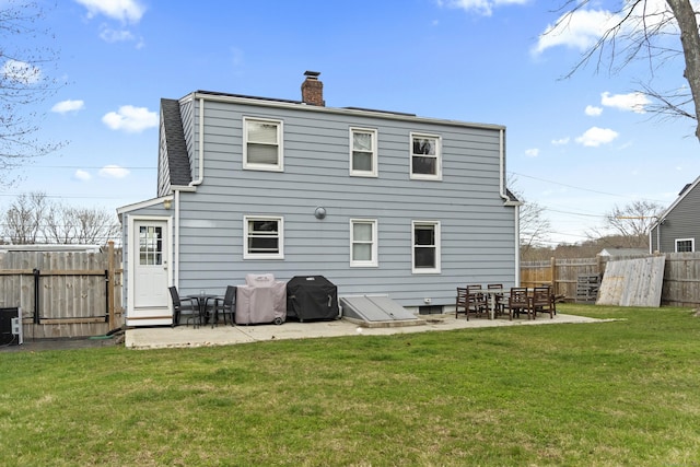 rear view of property with a yard, a fenced backyard, a patio, and a chimney