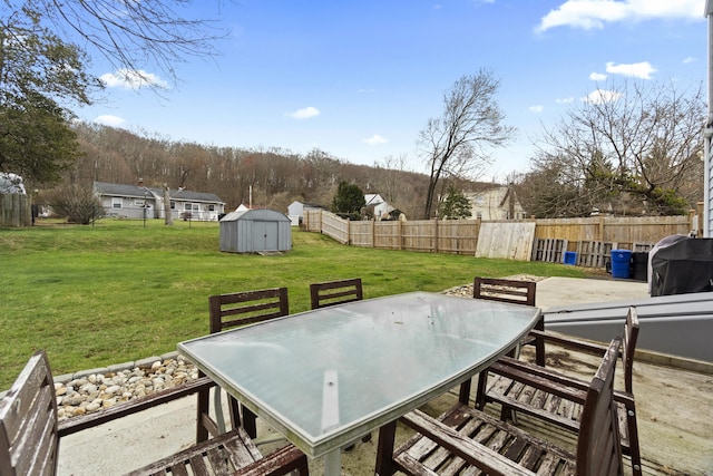 view of patio with an outdoor structure, a fenced backyard, a storage unit, and outdoor dining area