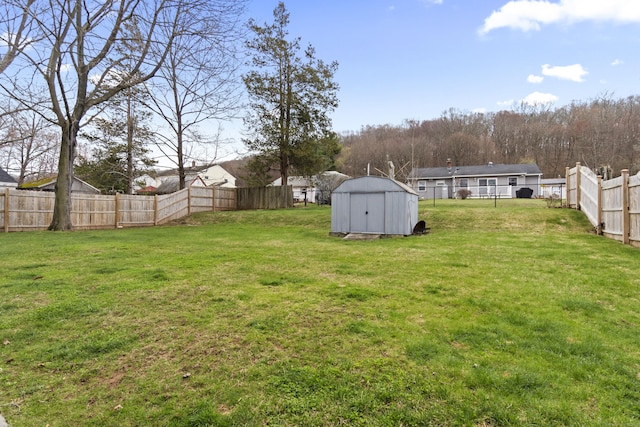 view of yard with a fenced backyard, an outbuilding, and a storage shed
