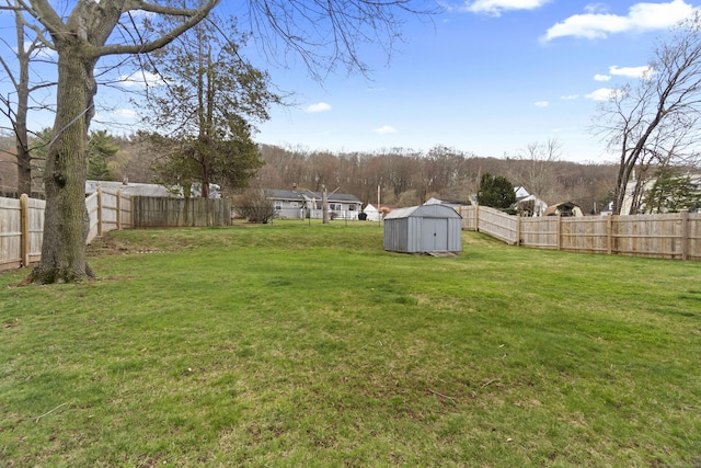 view of yard with a fenced backyard, an outdoor structure, and a storage shed