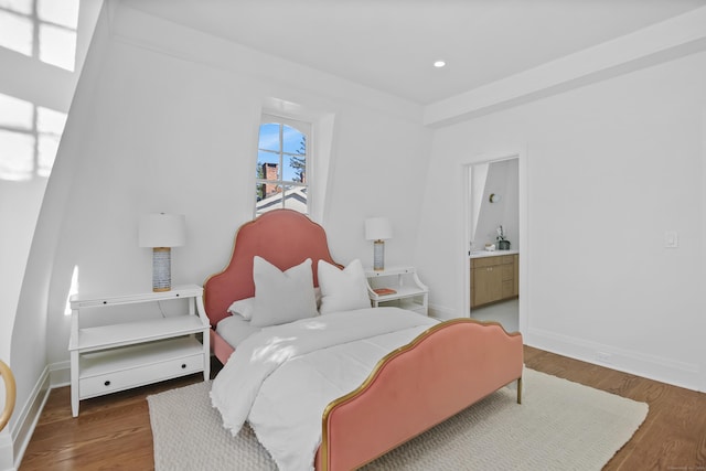 bedroom featuring baseboards, recessed lighting, ensuite bath, and wood finished floors