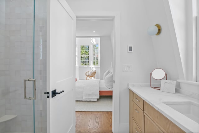 ensuite bathroom with vanity, wood finished floors, ensuite bathroom, baseboards, and a shower stall