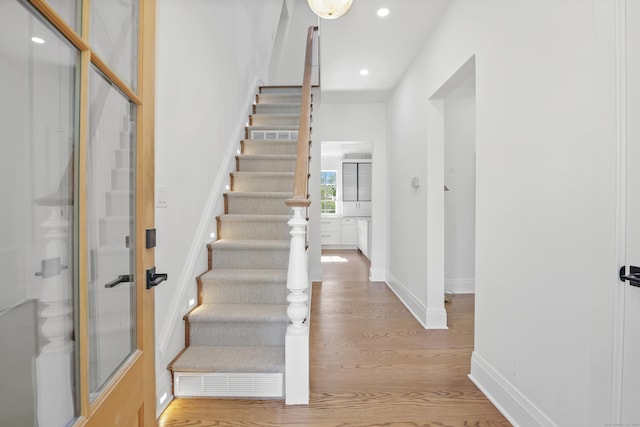 staircase with recessed lighting, baseboards, and wood finished floors