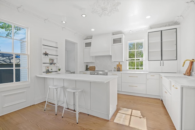 kitchen featuring a sink, light wood-style floors, light countertops, a peninsula, and a kitchen bar