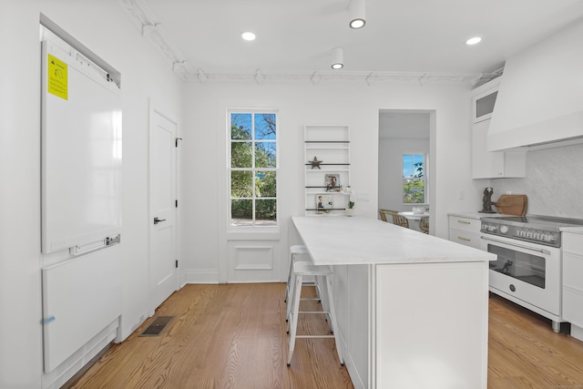 kitchen featuring visible vents, light wood-type flooring, light countertops, white cabinetry, and electric stove