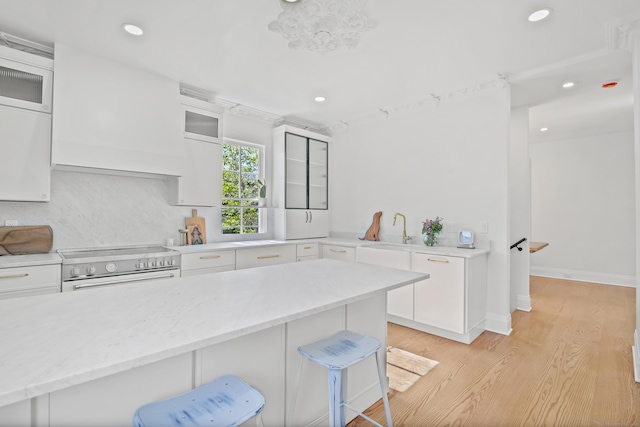 kitchen with high end stove, a sink, white cabinets, and a breakfast bar