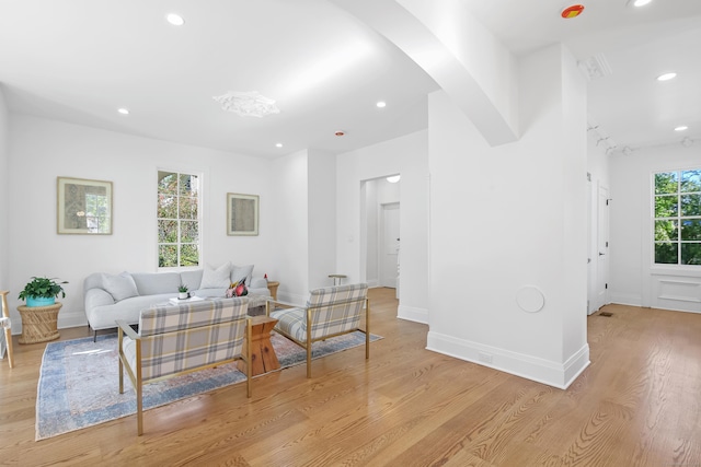 living area with recessed lighting, arched walkways, light wood finished floors, and baseboards