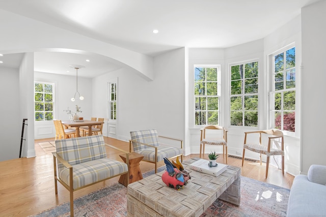 living area with light wood-style floors, arched walkways, recessed lighting, baseboards, and visible vents