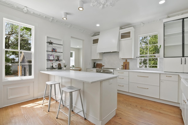 66 Seminary St, New Canaan, CT 06840 - kitchen with white cabinetry, custom exhaust hood, plenty of natural light, light countertops, and recessed lighting