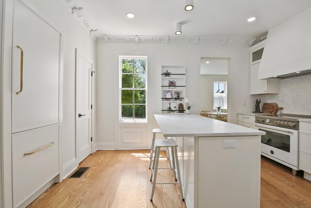 66 Seminary St, New Canaan, CT 06840 - kitchen with white range with electric stovetop, white cabinets, healthy amount of natural light, light wood finished floors, and recessed lighting