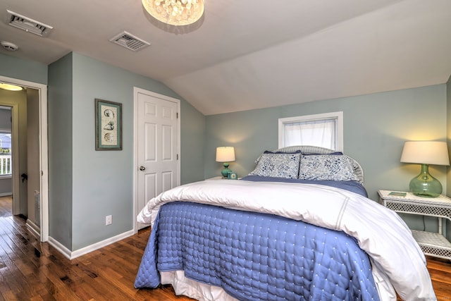 bedroom featuring wood finished floors, baseboards, vaulted ceiling, and visible vents