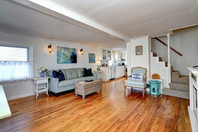 living area with baseboards, visible vents, light wood finished floors, and stairs