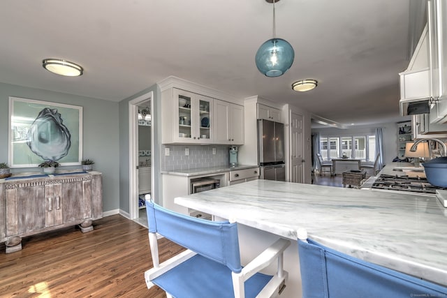 kitchen with dark wood finished floors, a sink, freestanding refrigerator, glass insert cabinets, and tasteful backsplash