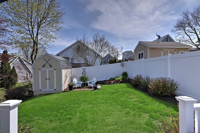 view of yard with a fenced backyard, an outbuilding, and a storage shed