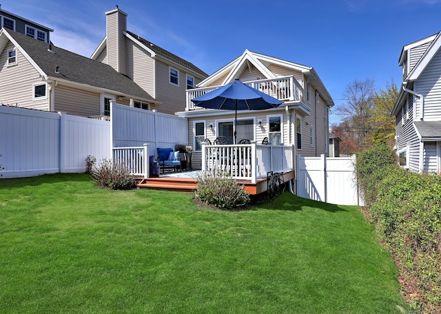 back of property with fence, a lawn, and a deck