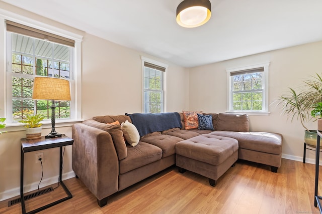 living room with baseboards, visible vents, a healthy amount of sunlight, and light wood-style flooring