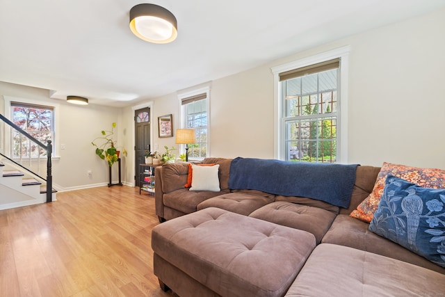 living area featuring stairway, baseboards, plenty of natural light, and light wood-style floors