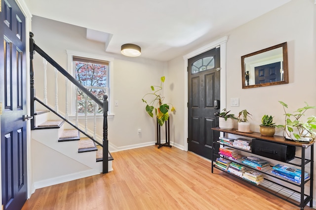 foyer entrance with baseboards, stairs, and light wood-style floors