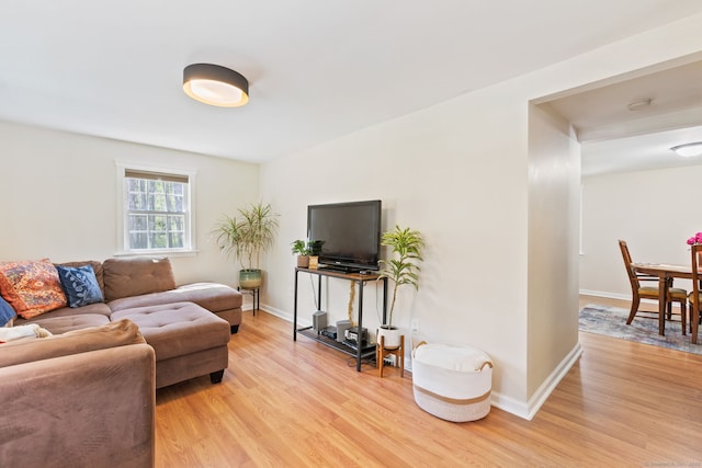living area featuring baseboards and light wood finished floors